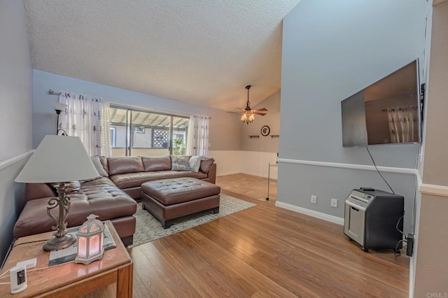 living room featuring ceiling fan, lofted ceiling, a textured ceiling, and light wood-type flooring