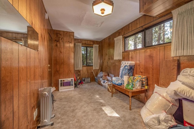 sitting room featuring radiator heating unit, light carpet, and wooden walls