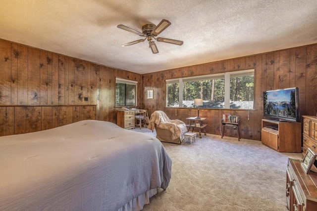 bedroom featuring a textured ceiling, ceiling fan, carpet, and wood walls