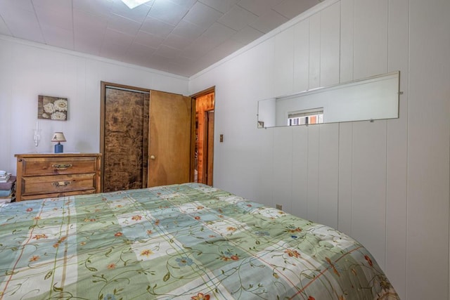 bedroom with crown molding, a closet, and wooden walls