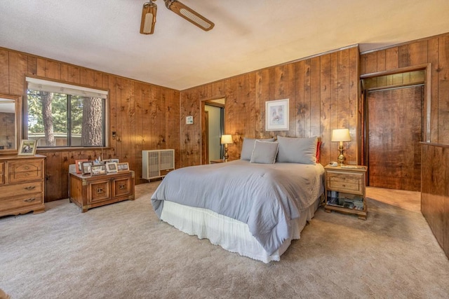 bedroom with carpet floors, ceiling fan, and wood walls