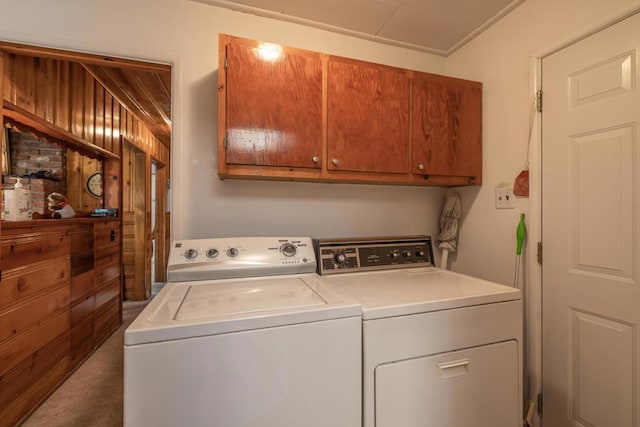 laundry room with cabinets, independent washer and dryer, and wood walls