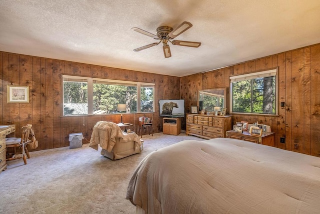 carpeted bedroom featuring multiple windows, wood walls, and ceiling fan