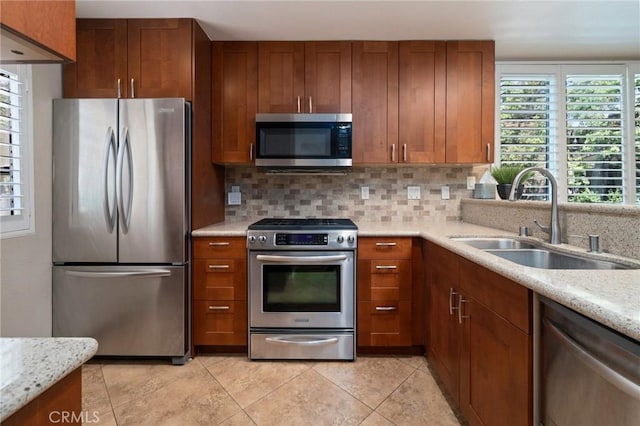 kitchen with tasteful backsplash, light stone counters, sink, and stainless steel appliances