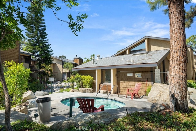 rear view of property featuring a patio and a pool