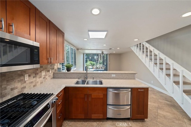 kitchen with kitchen peninsula, tasteful backsplash, stainless steel appliances, ceiling fan, and sink