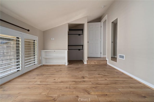 unfurnished bedroom with light hardwood / wood-style floors and lofted ceiling