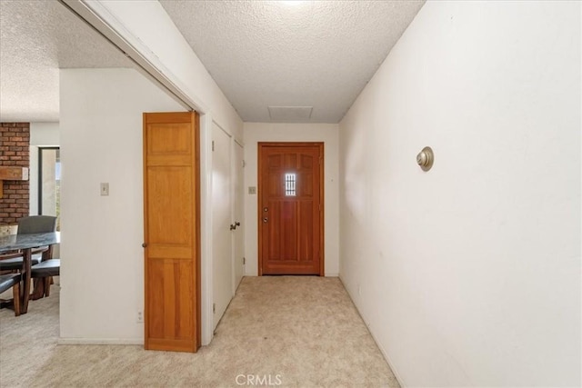 doorway featuring light carpet and a textured ceiling