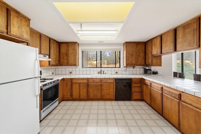 kitchen featuring tile countertops, plenty of natural light, white appliances, and sink