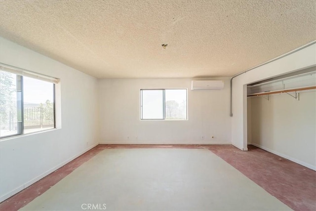 unfurnished bedroom with an AC wall unit, a closet, and a textured ceiling