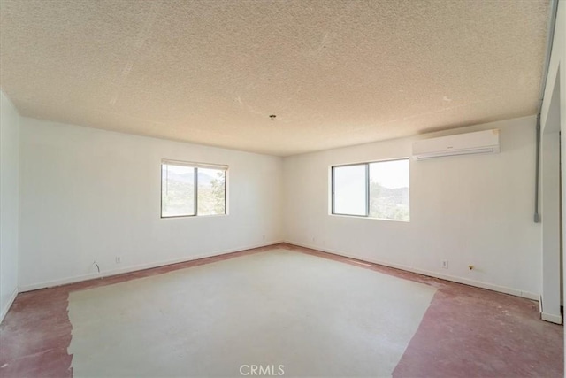 empty room featuring a textured ceiling, an AC wall unit, and a healthy amount of sunlight