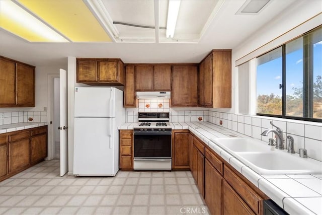 kitchen with white appliances, tile countertops, tasteful backsplash, and sink