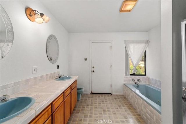 bathroom featuring tiled bath, vanity, and toilet