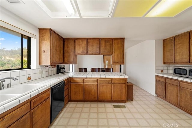 kitchen featuring tile countertops, dishwasher, decorative backsplash, and kitchen peninsula