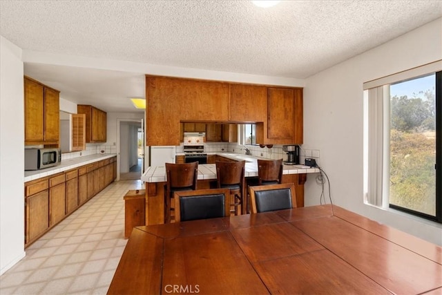 kitchen featuring tile countertops, a healthy amount of sunlight, stainless steel appliances, and a textured ceiling