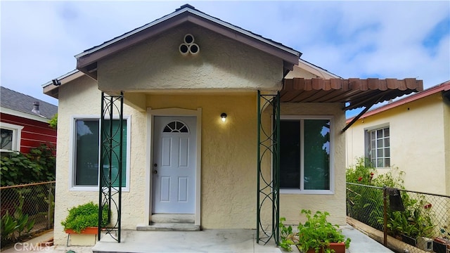 property entrance with fence and stucco siding