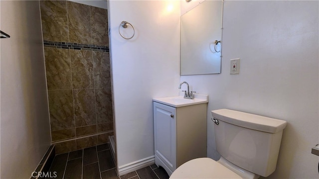 bathroom with tiled shower, vanity, and toilet