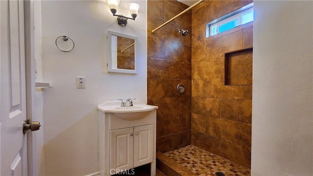 full bathroom with tiled shower and vanity