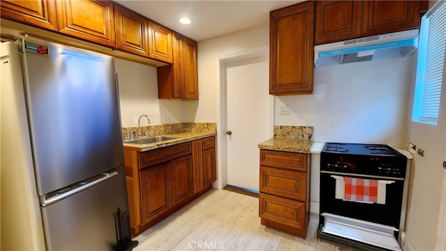 kitchen with stainless steel fridge, sink, light hardwood / wood-style floors, black range oven, and range hood