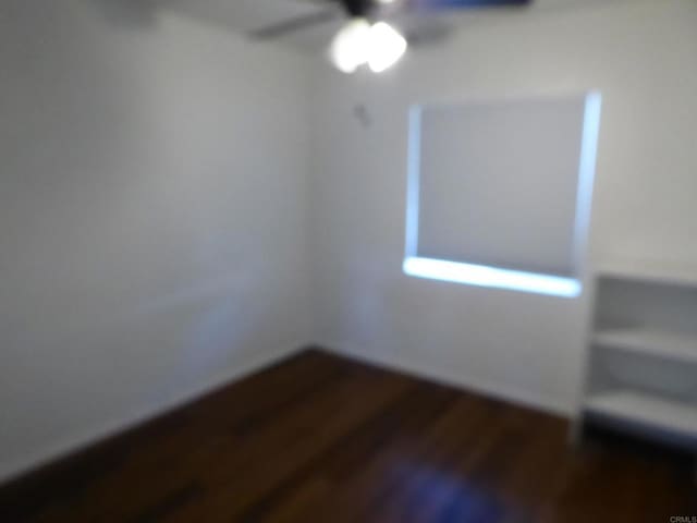 empty room with ceiling fan and dark wood-type flooring