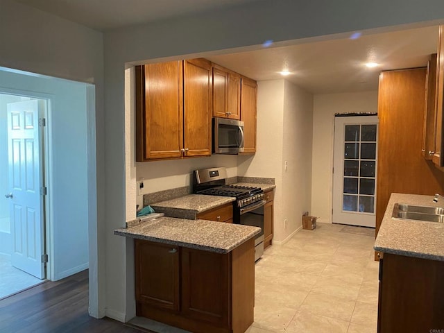 kitchen with appliances with stainless steel finishes, light wood-type flooring, and sink