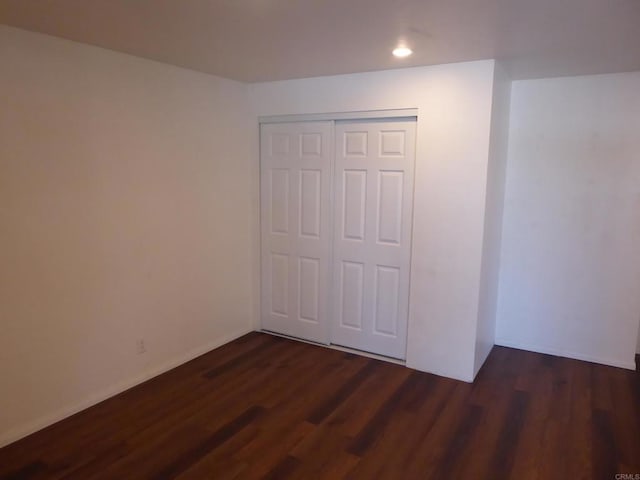 unfurnished bedroom with a closet and dark hardwood / wood-style floors