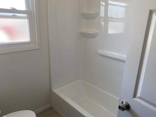 full bath featuring plenty of natural light, toilet, and baseboards