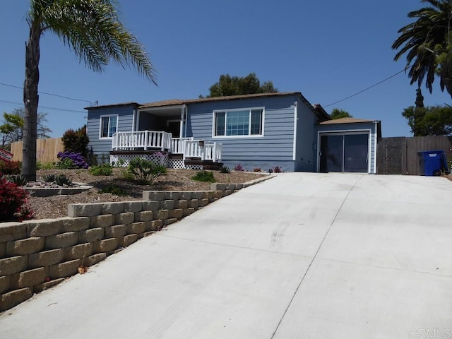 view of front of house with concrete driveway, a porch, an attached garage, and fence