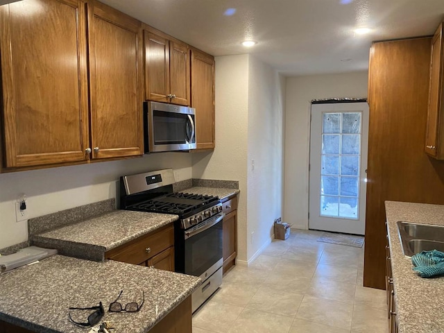 kitchen with stainless steel appliances, brown cabinetry, and a sink