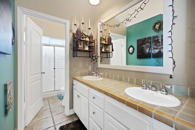 bathroom featuring vanity, toilet, and a shower with shower door