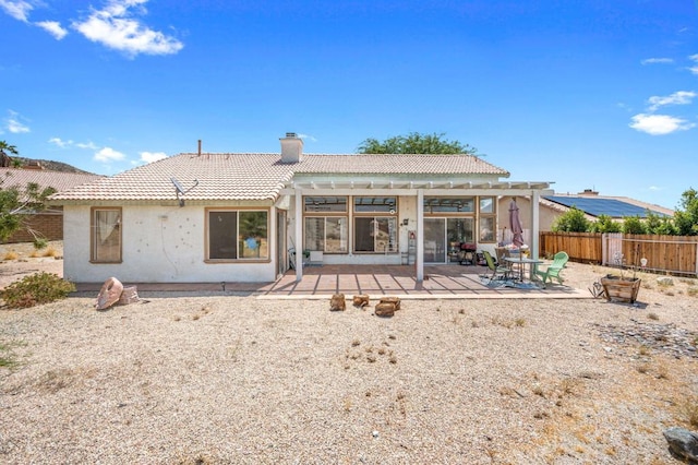 rear view of property featuring a pergola and a patio area