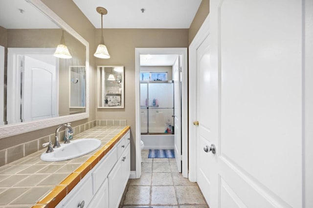 full bathroom featuring vanity, shower / bath combination with glass door, and toilet