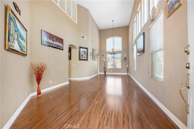 entryway featuring a towering ceiling, a chandelier, and dark hardwood / wood-style flooring