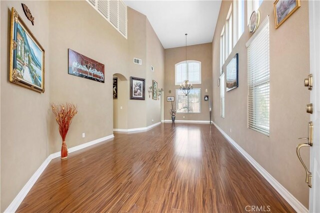 foyer entrance featuring dark hardwood / wood-style flooring, a chandelier, and a high ceiling