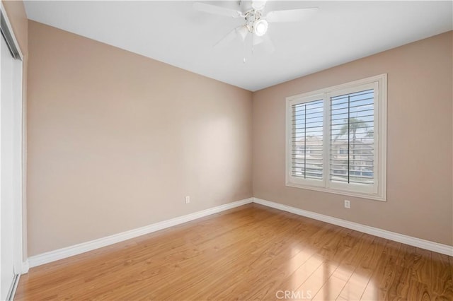 spare room with light wood-type flooring, ceiling fan, and baseboards