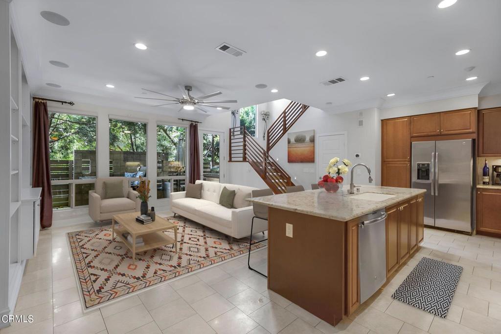 kitchen featuring a kitchen island with sink, sink, appliances with stainless steel finishes, light stone countertops, and ceiling fan