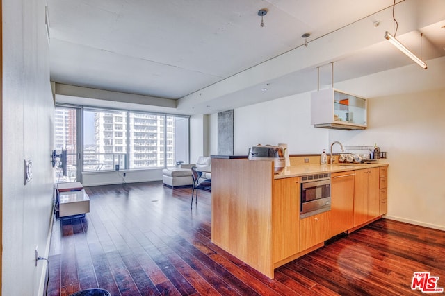 kitchen featuring dark hardwood / wood-style flooring, kitchen peninsula, sink, and stainless steel microwave