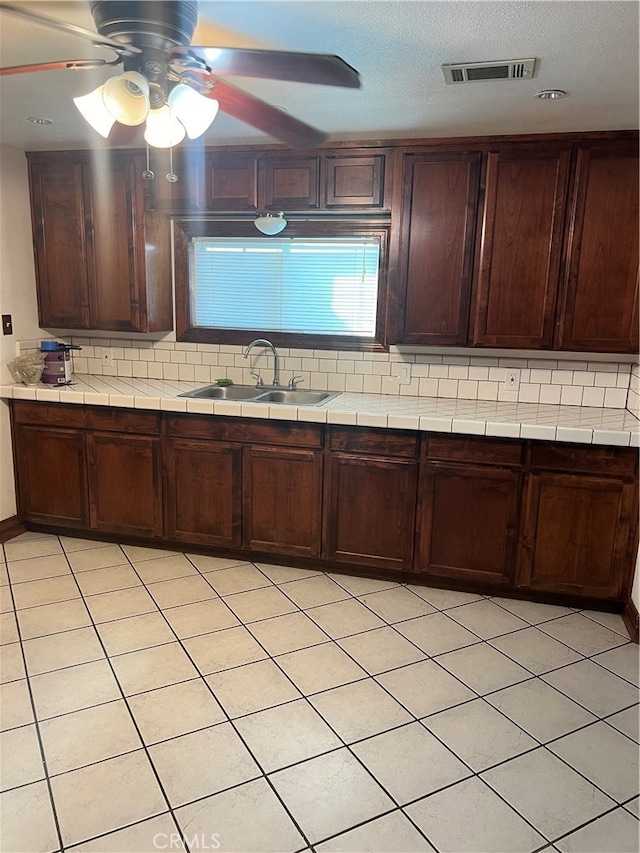 kitchen featuring dark brown cabinets, backsplash, ceiling fan, and sink