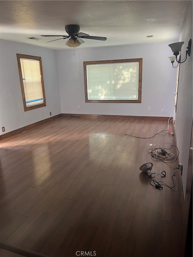 unfurnished room featuring a wealth of natural light, wood-type flooring, and ceiling fan