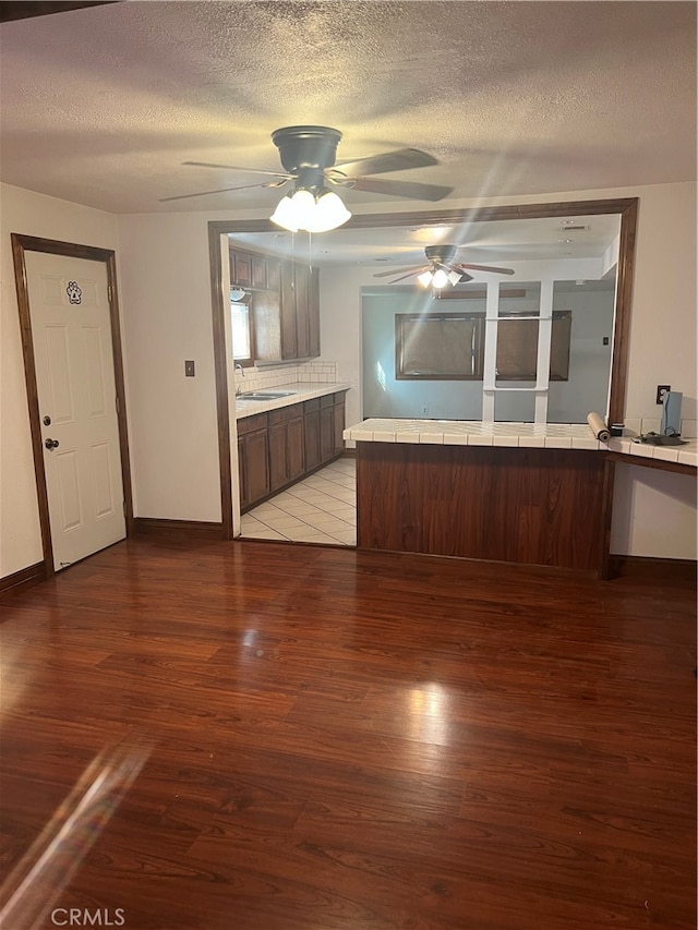 unfurnished living room with a textured ceiling, light hardwood / wood-style floors, ceiling fan, and sink