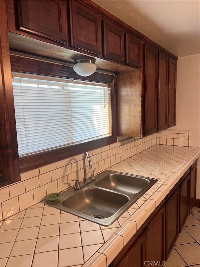 kitchen with light tile patterned flooring, tile counters, sink, and decorative backsplash