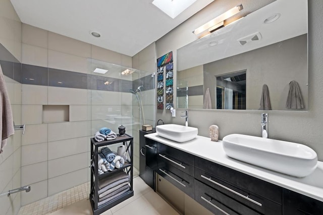 bathroom featuring vanity, tile patterned floors, a skylight, and tiled shower