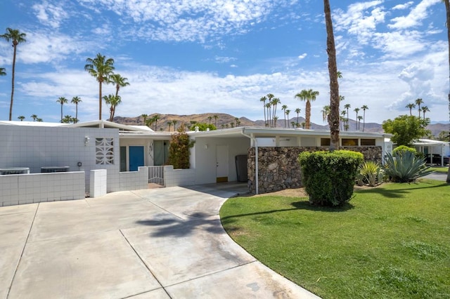 ranch-style house with cooling unit, a front lawn, a mountain view, and a carport