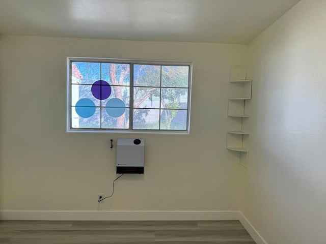 clothes washing area featuring heating unit and hardwood / wood-style flooring