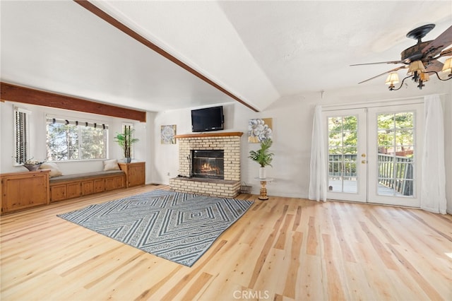 living room featuring ceiling fan, vaulted ceiling with beams, french doors, wood-type flooring, and a fireplace