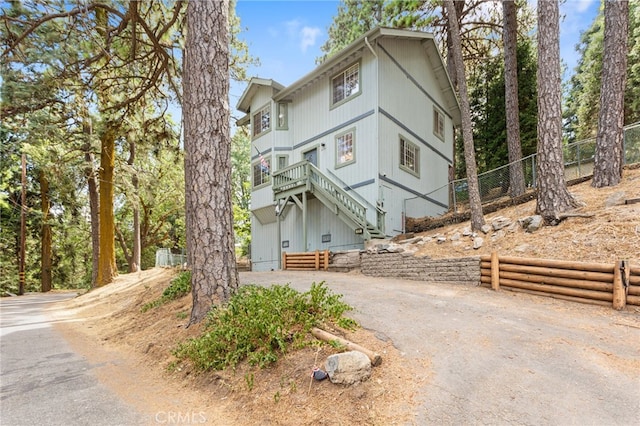 view of front of home featuring driveway, fence, and stairway