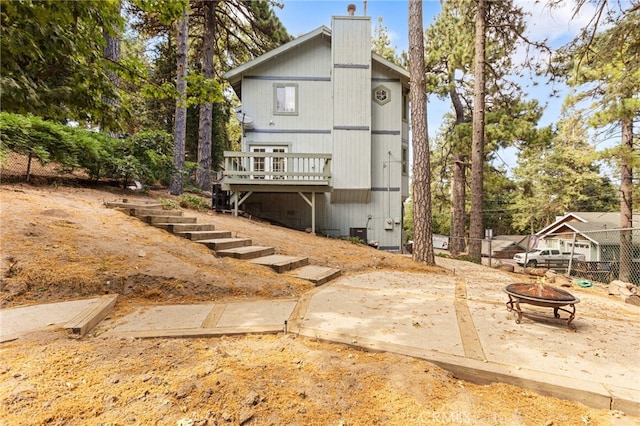 back of house featuring a wooden deck and an outdoor fire pit