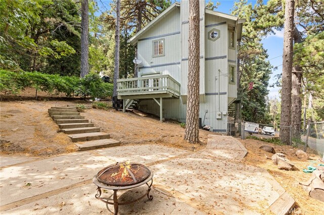 rear view of property with a fire pit, stairs, fence, a deck, and a patio area