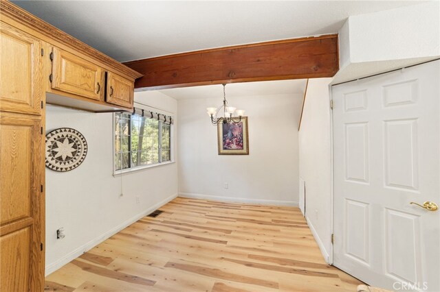 unfurnished dining area featuring light wood finished floors, baseboards, visible vents, an inviting chandelier, and beam ceiling