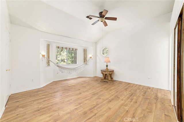 empty room featuring lofted ceiling, visible vents, baseboards, a ceiling fan, and light wood-type flooring